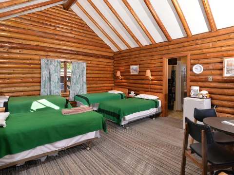 Interior view of the log cabin with multiple beds and a small table.