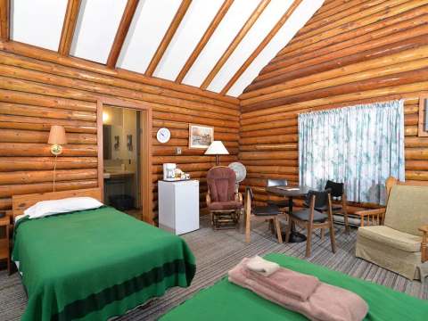 Interior view of the cabin featuring two beds, a dining table, and a small seating area.