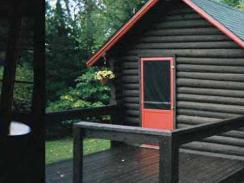 View of the exterior of cabin number 5 featuring its wooden deck and red door.