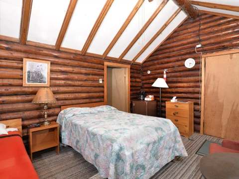 Bedroom with beds and wooden cathedral ceiling in a lodge cabin.