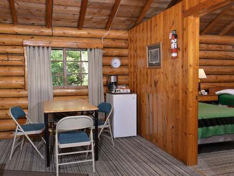 Coin repas et vue sur la chambre dans le chalet 9 tout en bois rond.