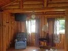 The log cabin's living area features a comfortable armchair and a television.