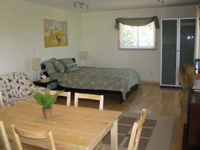 This spacious bedroom is equipped with a comfortable bed and a dining table.