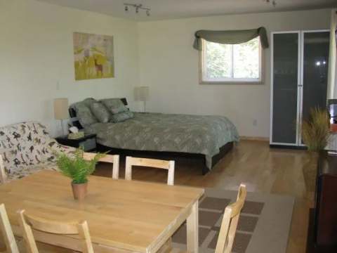 This spacious bedroom is equipped with a comfortable bed and a dining table.
