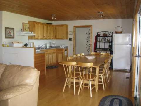 This open kitchen includes a wooden dining table and convenient storage spaces.