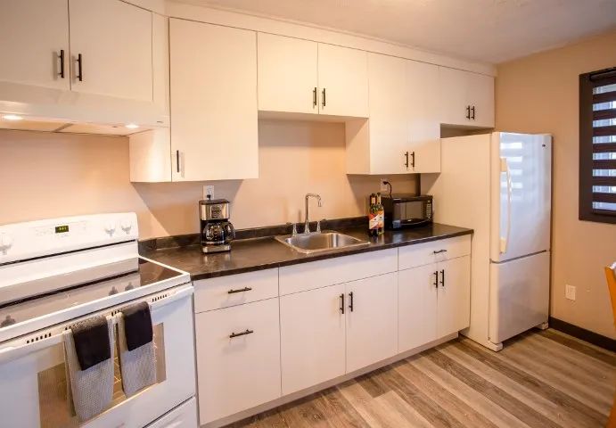 This suite features a functional kitchen equipped with modern appliances and white cabinets.