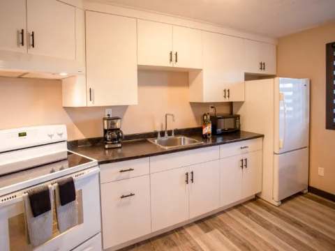 This suite features a functional kitchen equipped with modern appliances and white cabinets.