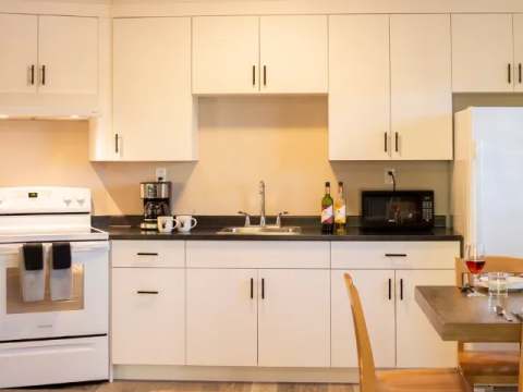 This equipped kitchen features a stove, a refrigerator, and a dining area.