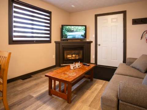 The suite living area features a fireplace, a television, and a comfortable sofa.