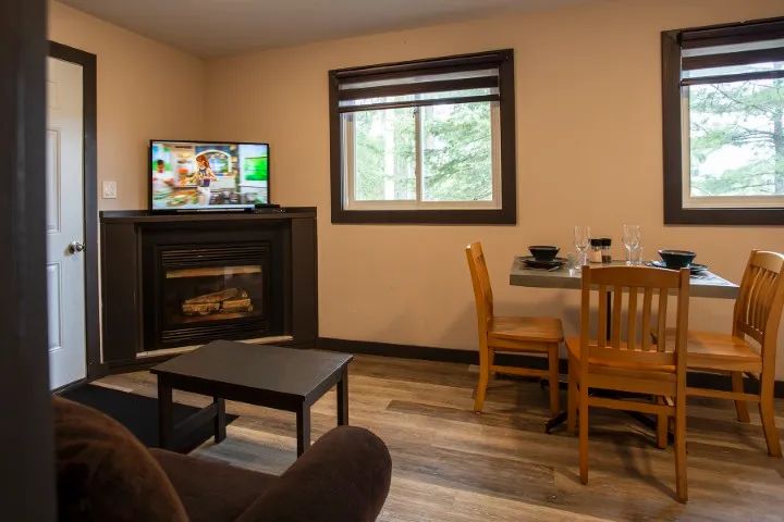 View of the suite's living room and dining area, featuring a fireplace and a television.