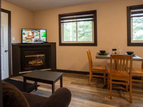View of the suite's living room and dining area, featuring a fireplace and a television.