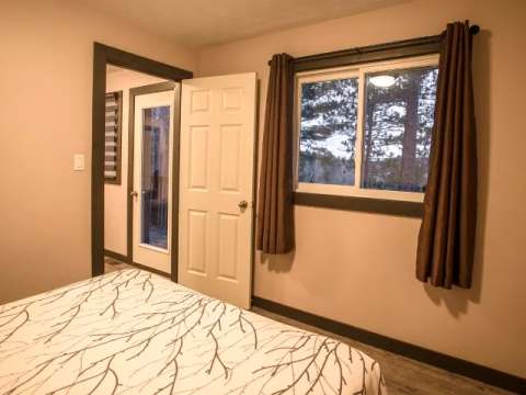 A view of the bedroom featuring the bed and a door leading to the private deck.