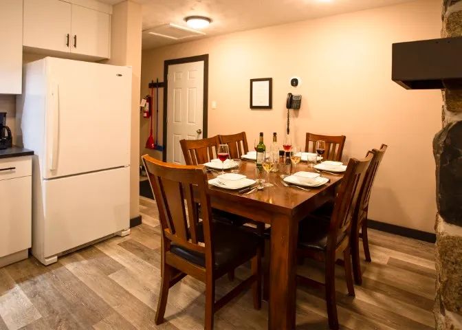 The suite's dining area features a wooden table with six chairs and a refrigerator.