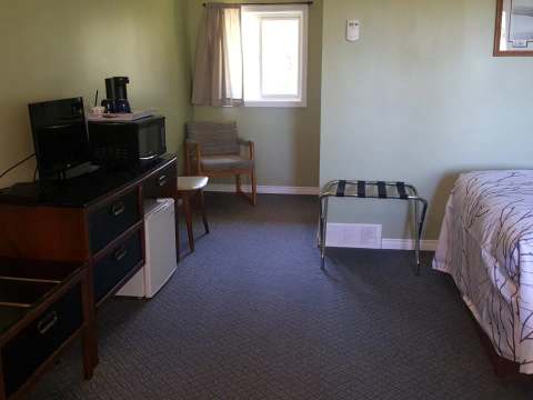 Cette unité de motel comprend un lit, un coin bureau avec cafetière et un espace de rangement.