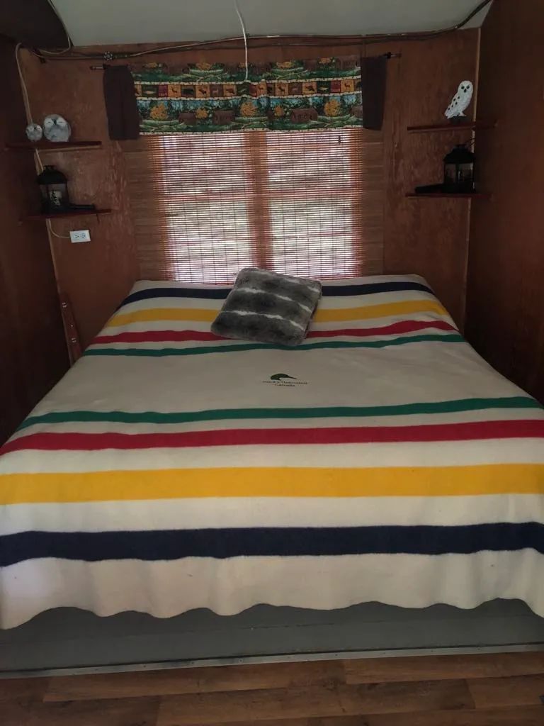 Une chambre confortable avec un lit double et des décorations rustiques au camp Serpentine.