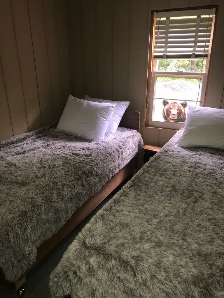 Deux lits simples avec couvertures douces dans une chambre du Serpentine Camp.