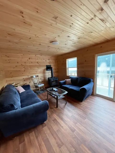 The cabin living room offers a comfortable relaxation space with its wood stove.