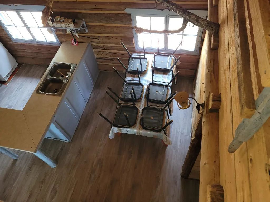 Vue plongeante sur la cuisine et la salle à manger du camp en bois rond.