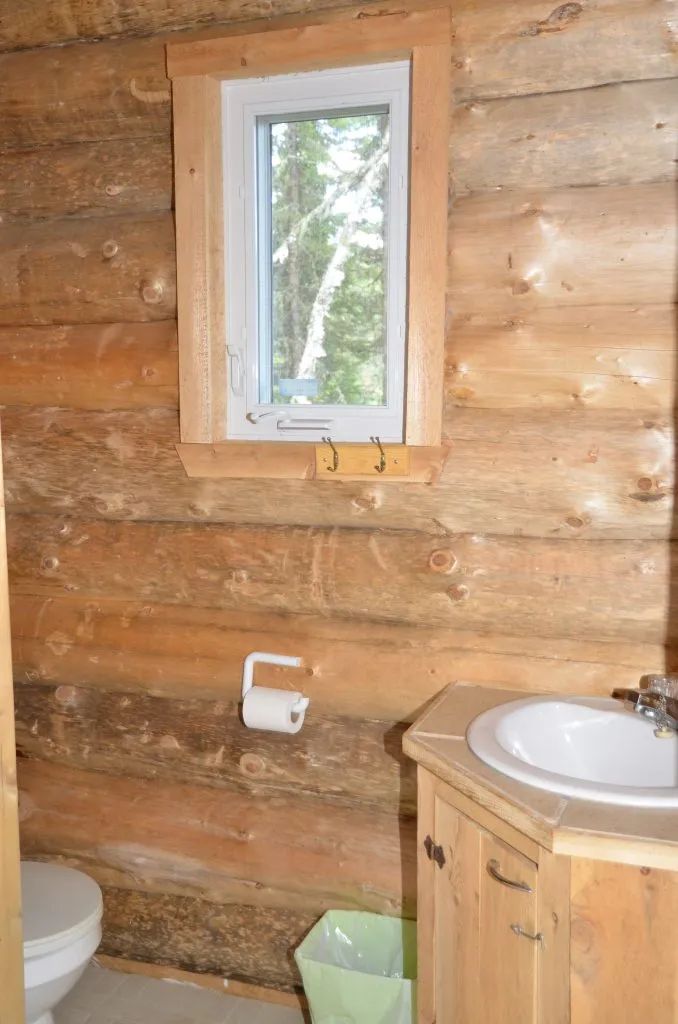 Vue de la salle de bain en bois rond du Camp Refuge.