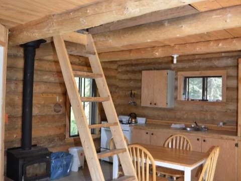 L'intérieur du camp comprend une cuisine fonctionnelle, une table à manger et un poêle à bois.