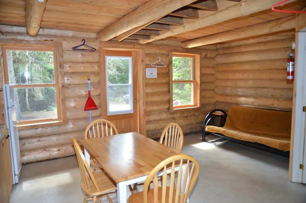 L'espace de vie du camp comprend une table à manger et un canapé-lit en bois rond.
