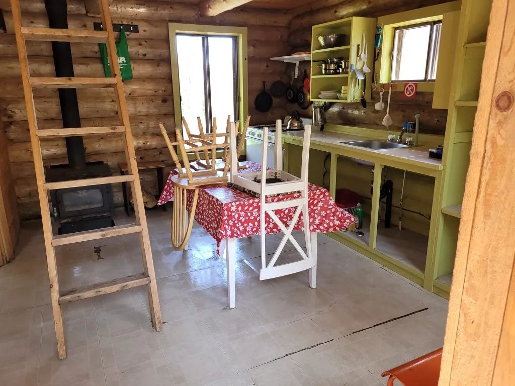 Cette cuisine rustique dispose d'un poêle à bois, d'une table à manger et d'un comptoir fonctionnel.