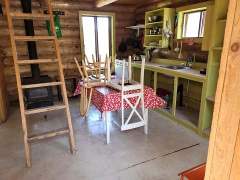 Cette cuisine rustique dispose d'un poêle à bois, d'une table à manger et d'un comptoir fonctionnel.