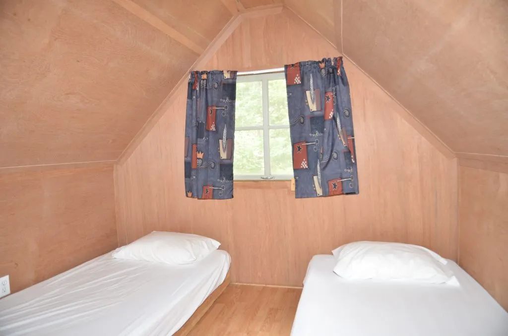 Cette chambre sous le toit du camp Refuge est aménagée avec deux lits simples.