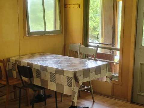 La salle à manger du camp Villa-Dama dispose d'une table avec chaises et d'une vue sur l'extérieur.