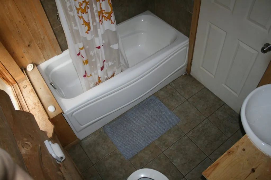 La salle de bain du chalet comprend une baignoire avec douche et un lavabo.