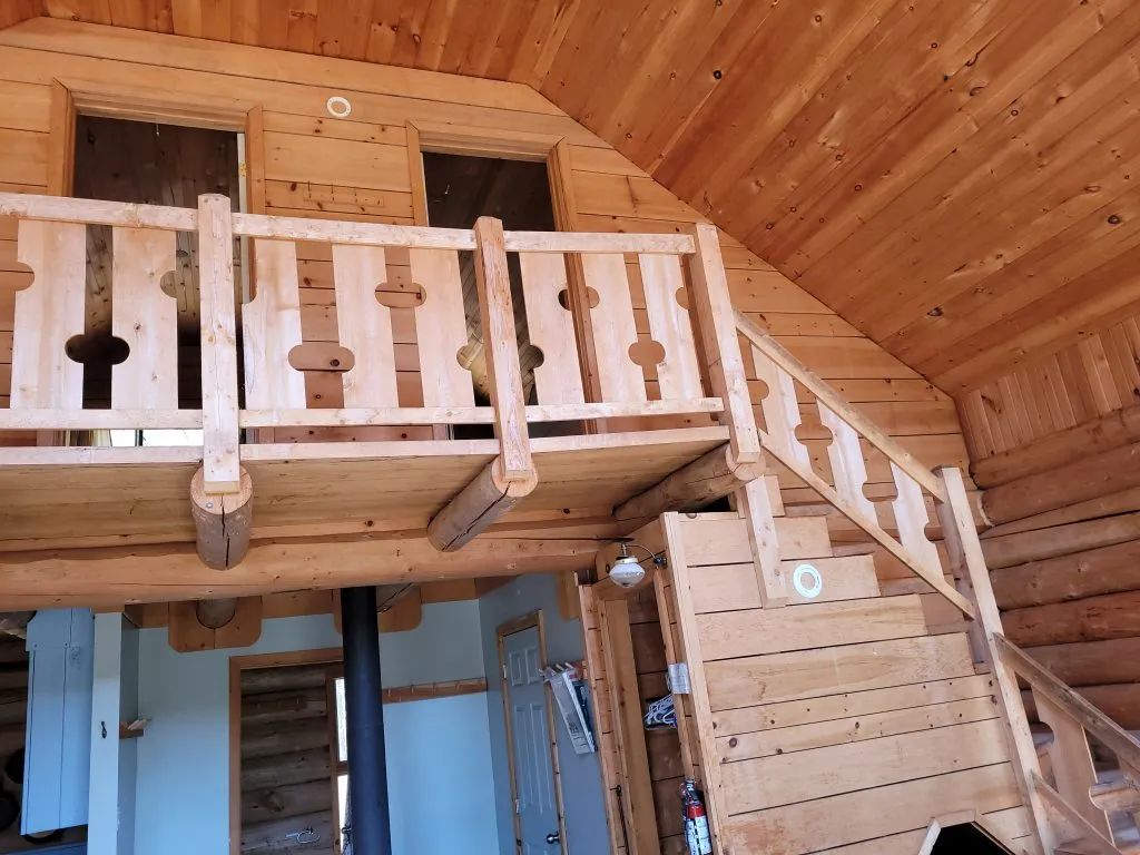 Vue intérieure du chalet montrant la mezzanine en bois et l'escalier menant à l'étage.