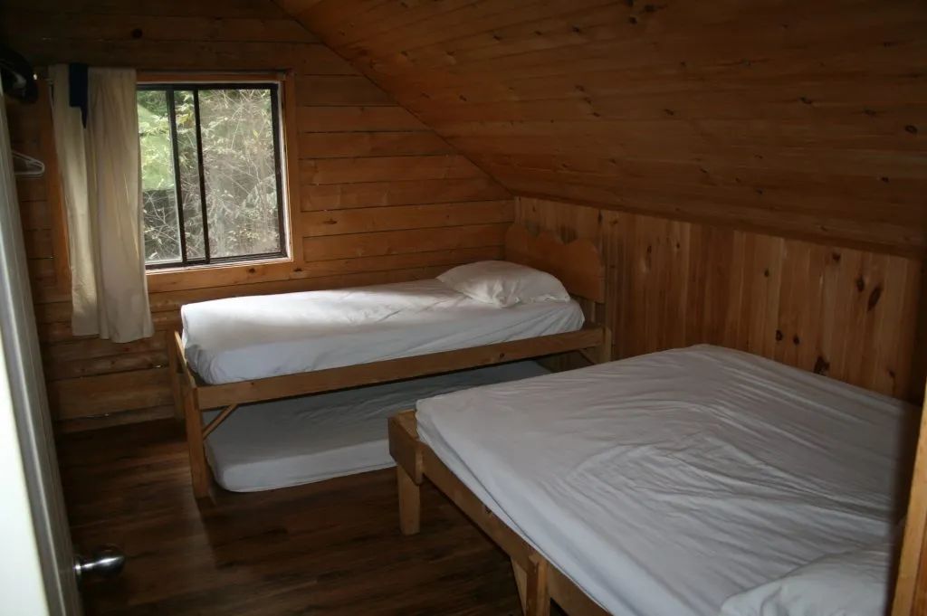 Cette chambre mansardée en bois propose des lits simples et doubles pour votre séjour.