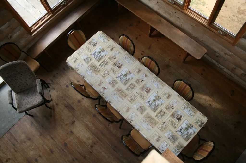 La salle à manger du chalet dispose d'une longue table avec des chaises et des bancs intégrés.