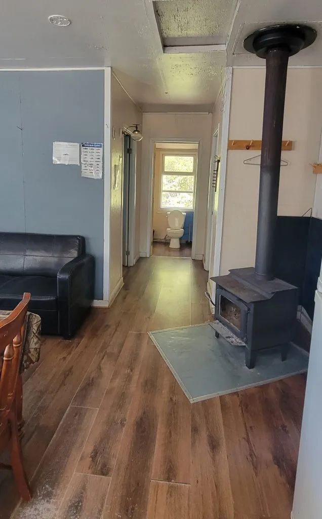 The cottage living area includes a wood stove, a sofa, and access to the bathroom.
