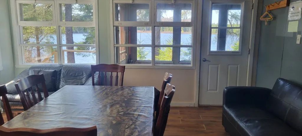 The cottage dining area offers a direct view of the lake and the surrounding forest.