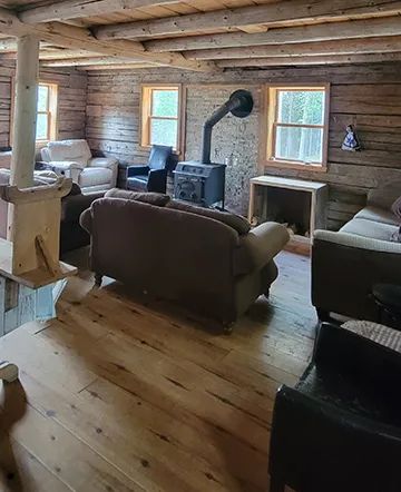 The cottage living room is furnished with comfortable sofas and a wood stove.