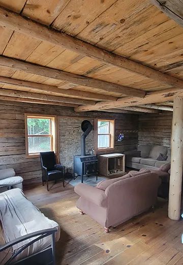 The cottage living room is furnished with a wood stove and comfortable seating areas.