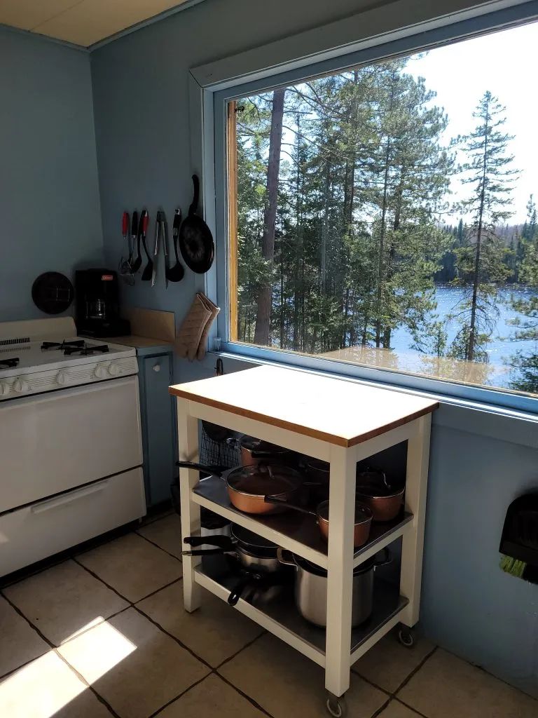 The cottage kitchen offers a stunning view of the forest and the water.