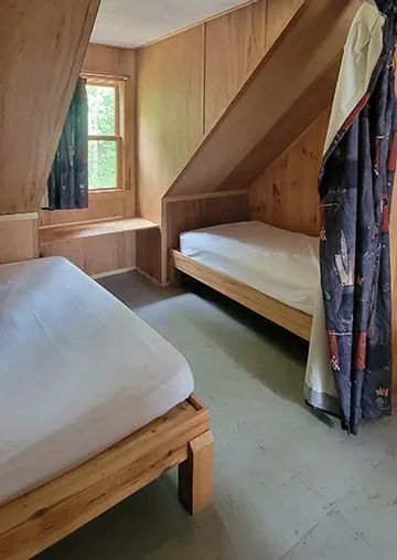 Bedroom located under the eaves with two single beds in the Des Pins cottage.
