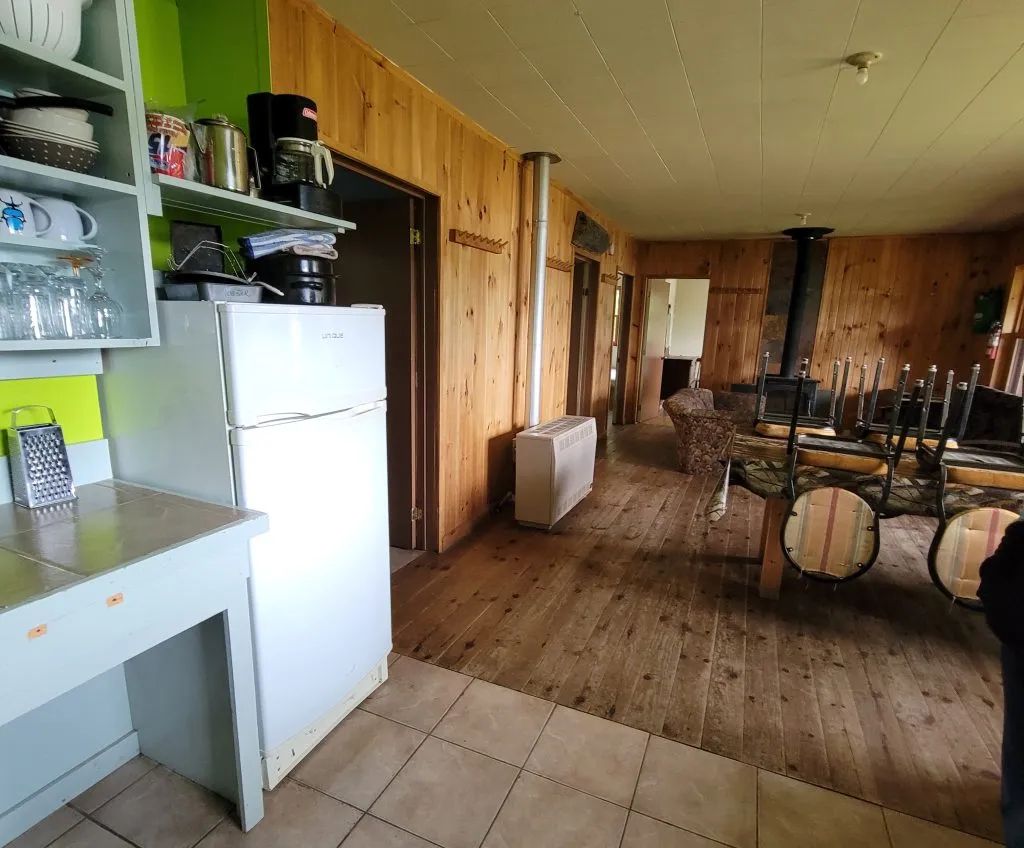 Vue sur la cuisine et le salon à aire ouverte du chalet, incluant un poêle à bois.