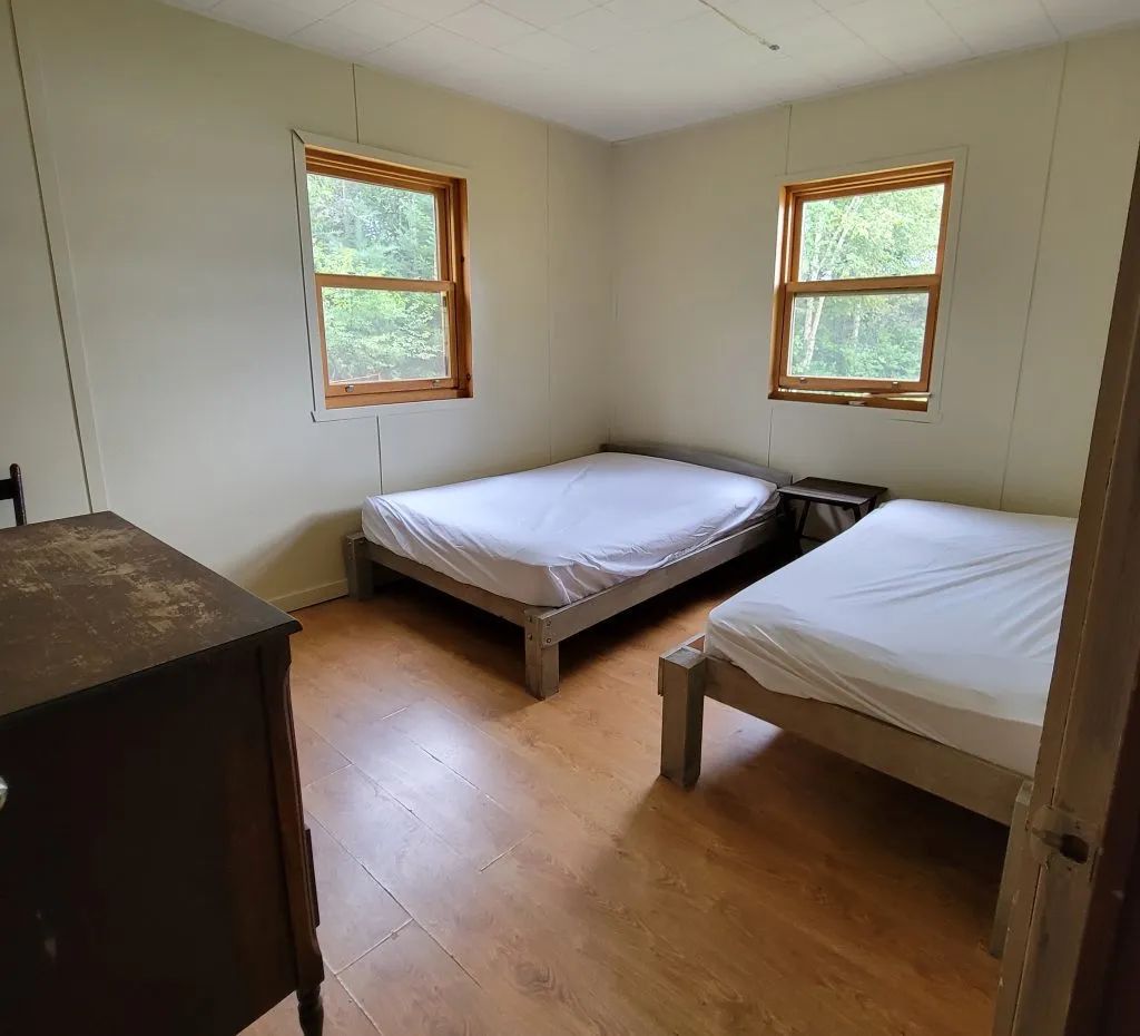 Cette chambre du Chalet Des Sables comprend deux lits simples avec une vue sur la forêt.
