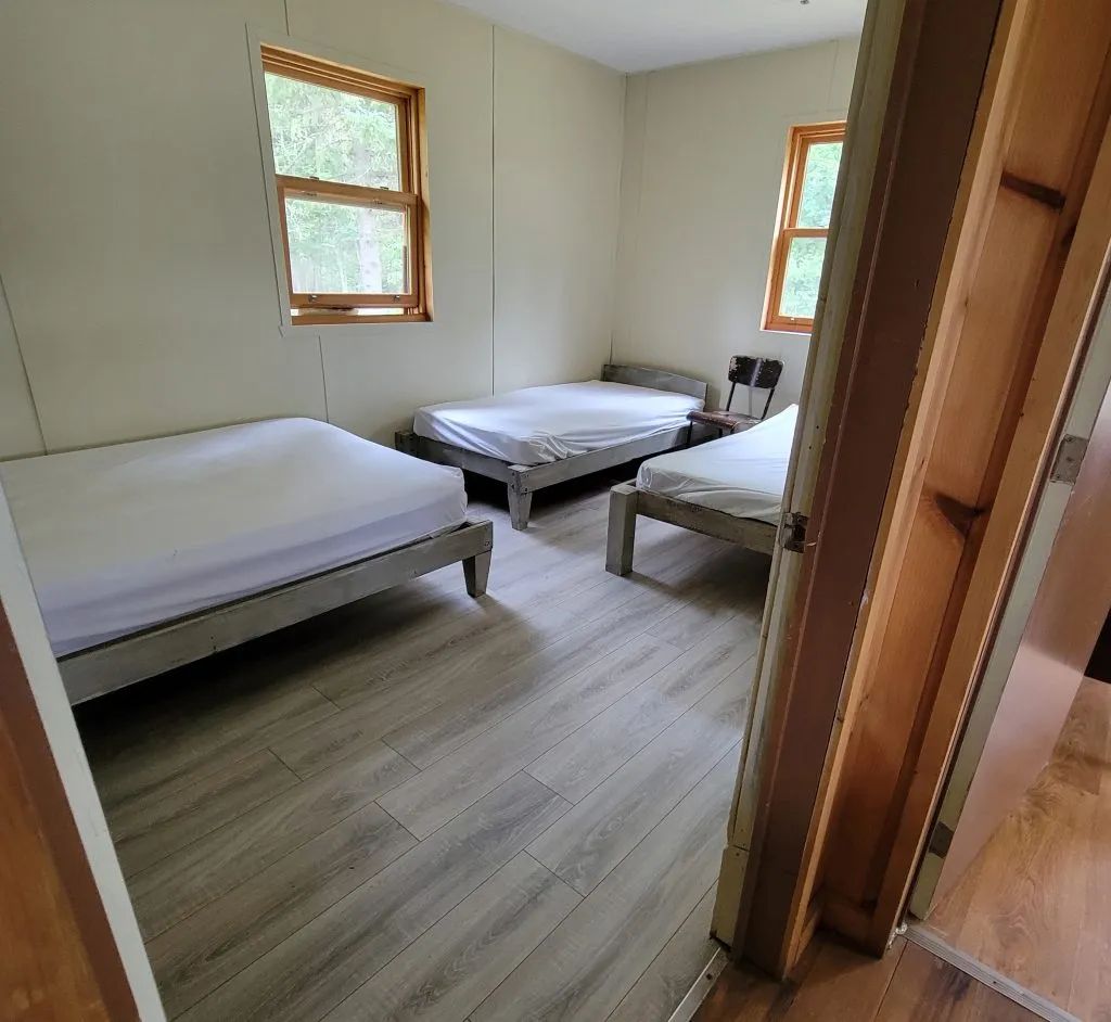 Cette chambre lumineuse du chalet dispose de trois lits simples avec vue sur la forêt.