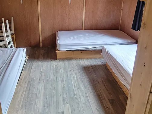 This bedroom in the Ducharme cottage is furnished with several single beds.