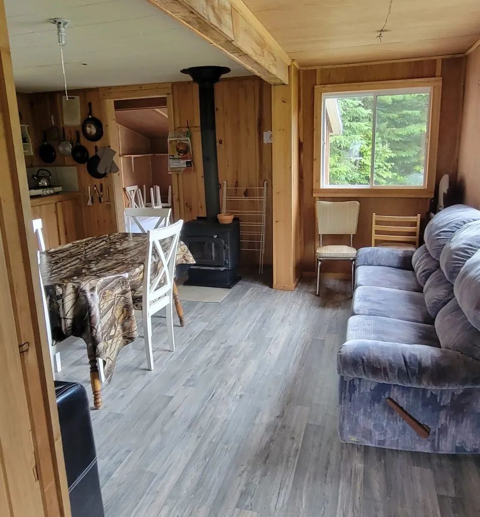 The open-concept living area of the cabin includes a kitchen space, a dining table, and a wood stove.