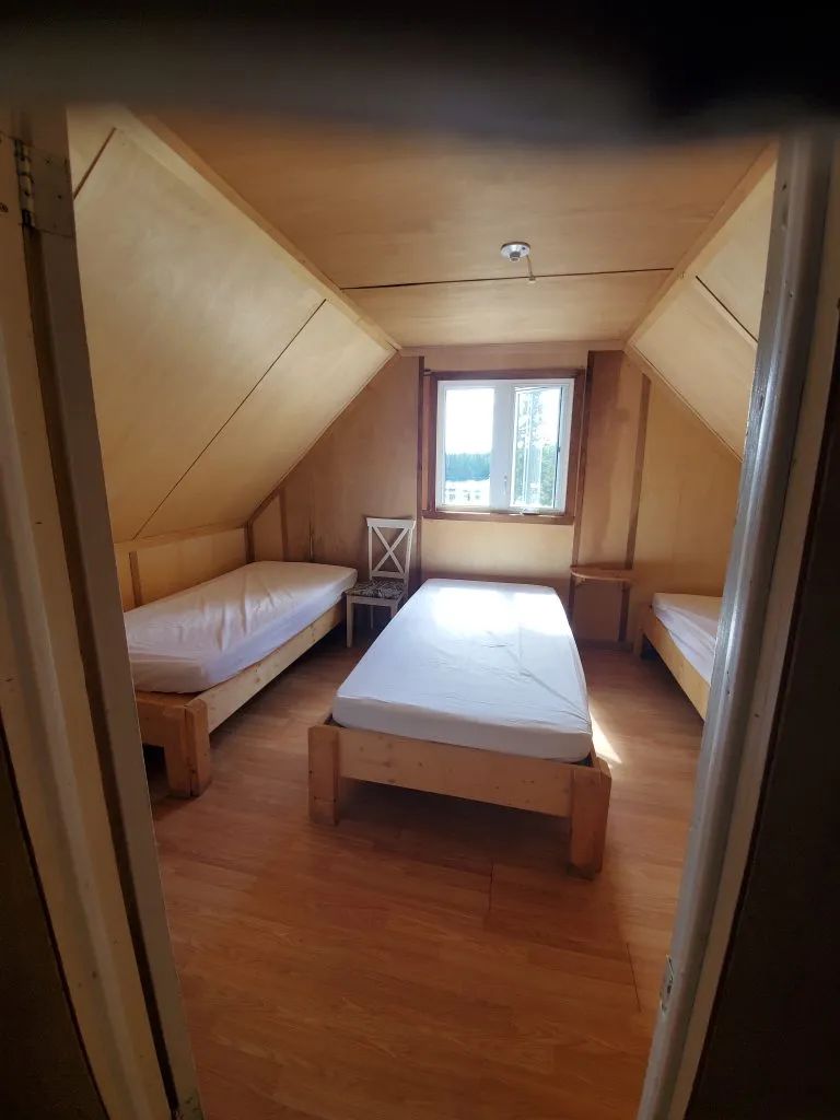 Vue sur la chambre à coucher avec trois lits simples dans le chalet Gobelin.