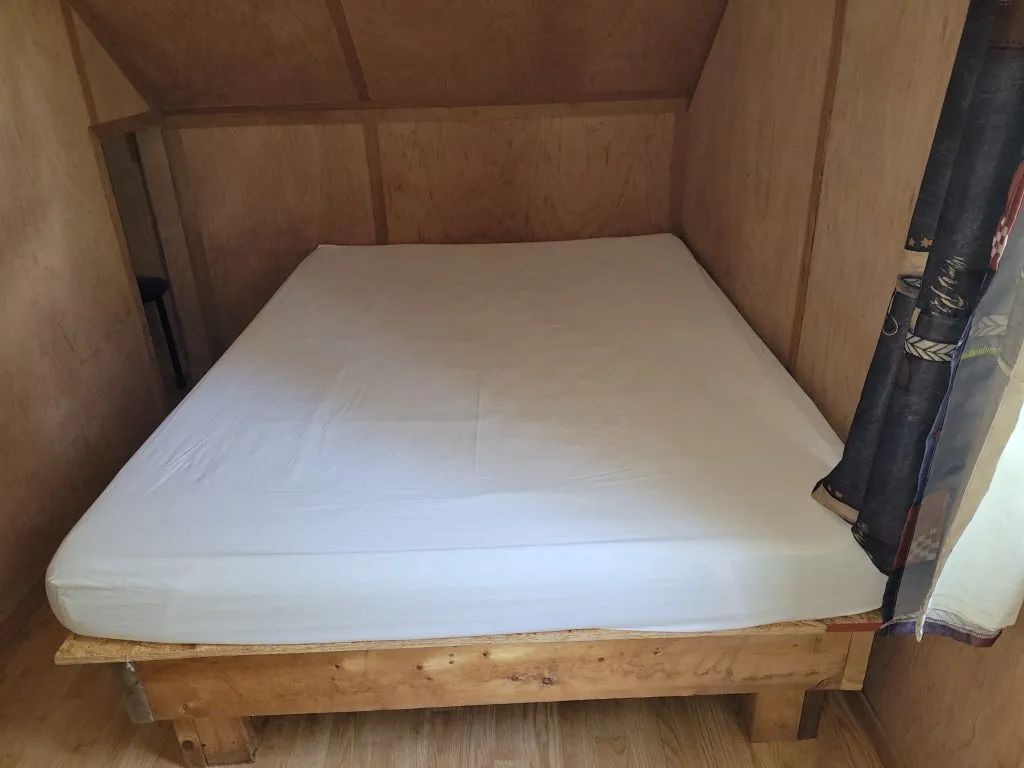 Lit double situé dans une chambre du chalet Huard avec murs et plafond en bois.