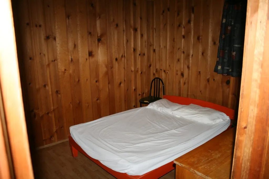 Cette chambre du chalet Jenny comprend un lit double avec des murs en lambris de bois.
