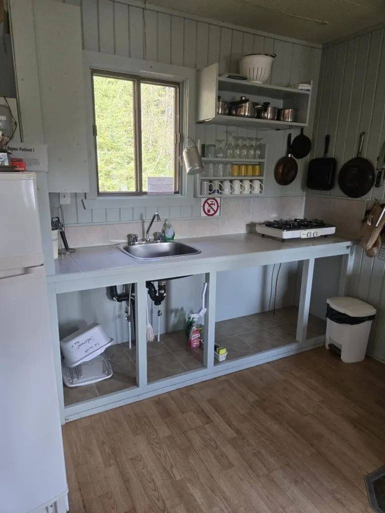 La cuisine fonctionnelle du chalet comprend un évier, une plaque de cuisson et des ustensiles.