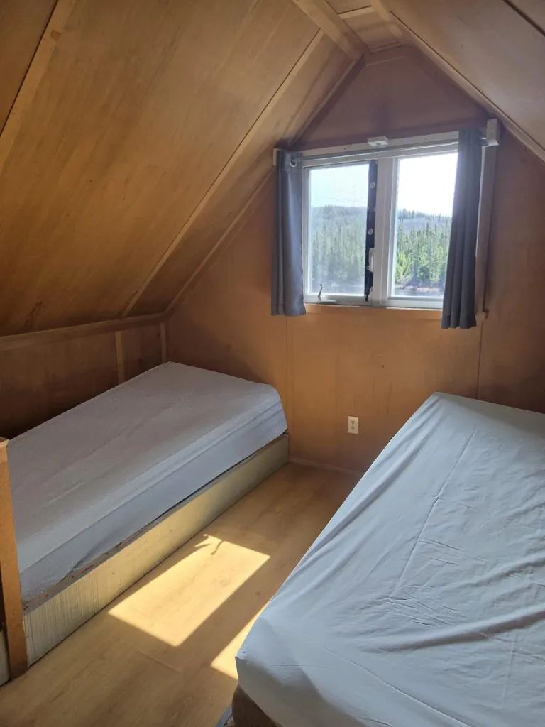 Cette chambre avec deux lits simples sous le toit offre une vue sur la forêt.