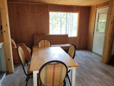 The dining area and living space of the Troll cabin offer a view of the surrounding forest.